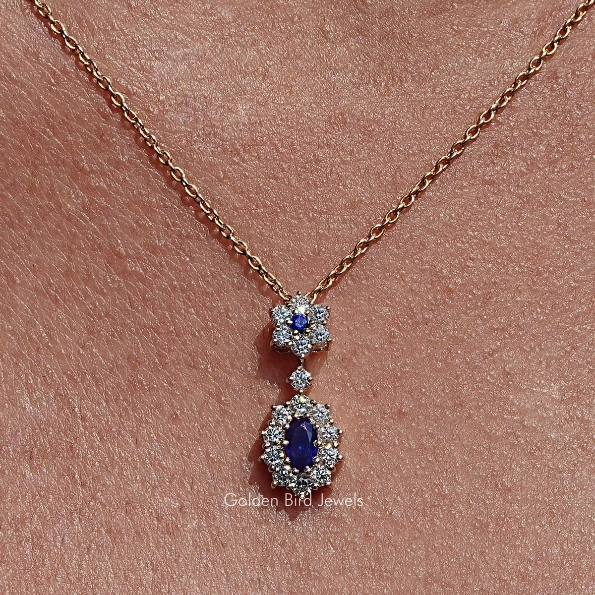 Gold-tone necklace pendant with two blue oval gemstones, each in a halo of clear stones