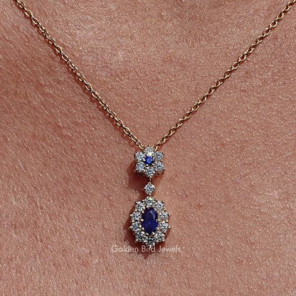 Gold-tone necklace pendant with two blue oval gemstones, each in a halo of clear stones