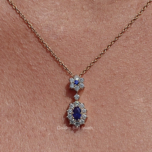 Gold-tone necklace pendant with two blue oval gemstones, each in a halo of clear stones