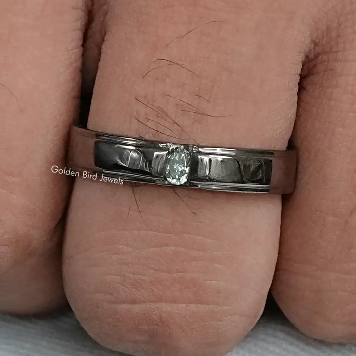 Men's wedding band with bright oval-cut stones on a dark metal band