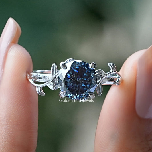 Silver moissanite ring with round blue center stone and leaf-style side settings