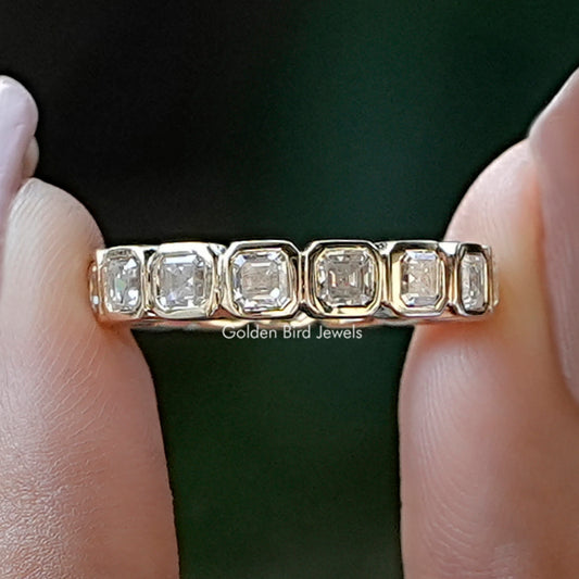 Square step-cut eternity band ring with clear stones on metal band, between fingers