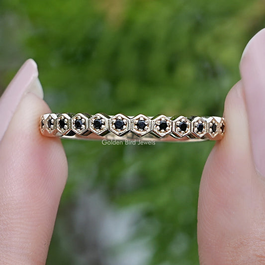 Half eternity ring with round dark gemstones on a gold-toned band