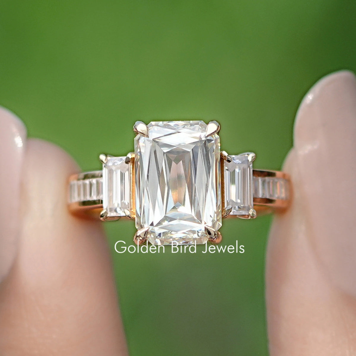 Close-up three-stone ring with large square-cut center stone and baguette side stones, gold-tone
