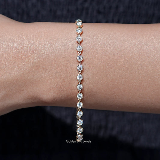 Gold-tone tennis bracelet with evenly spaced round clear stones in a straight line