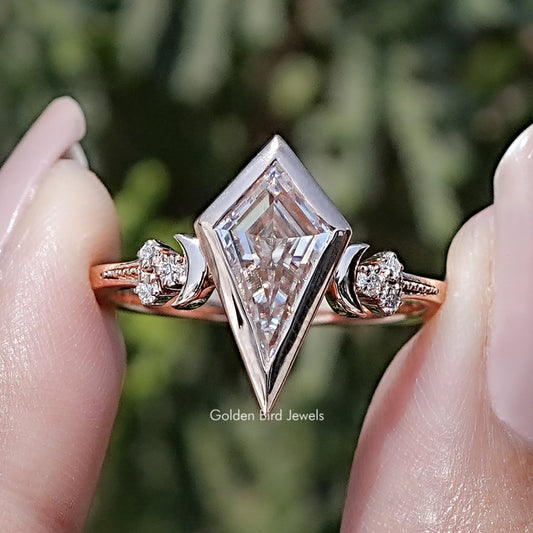 Rose-gold kite-cut moissanite bezel ring with round side stones and V-shaped prongs