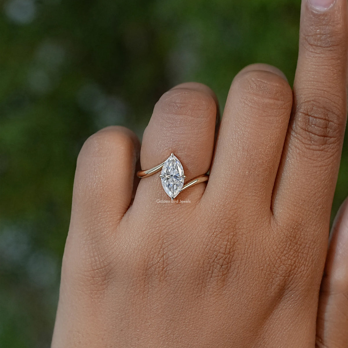 Marquise moissanite solitaire engagement ring on finger with slim gold-toned band