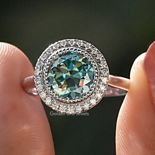 Moissanite halo bridal ring with round blue-green center stone and pavé band