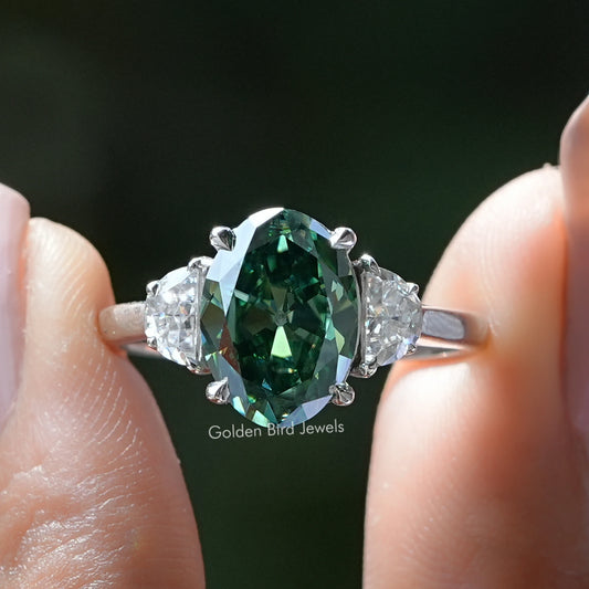Three-stone oval ring with dark green center stone and clear side stones, sterling silver band