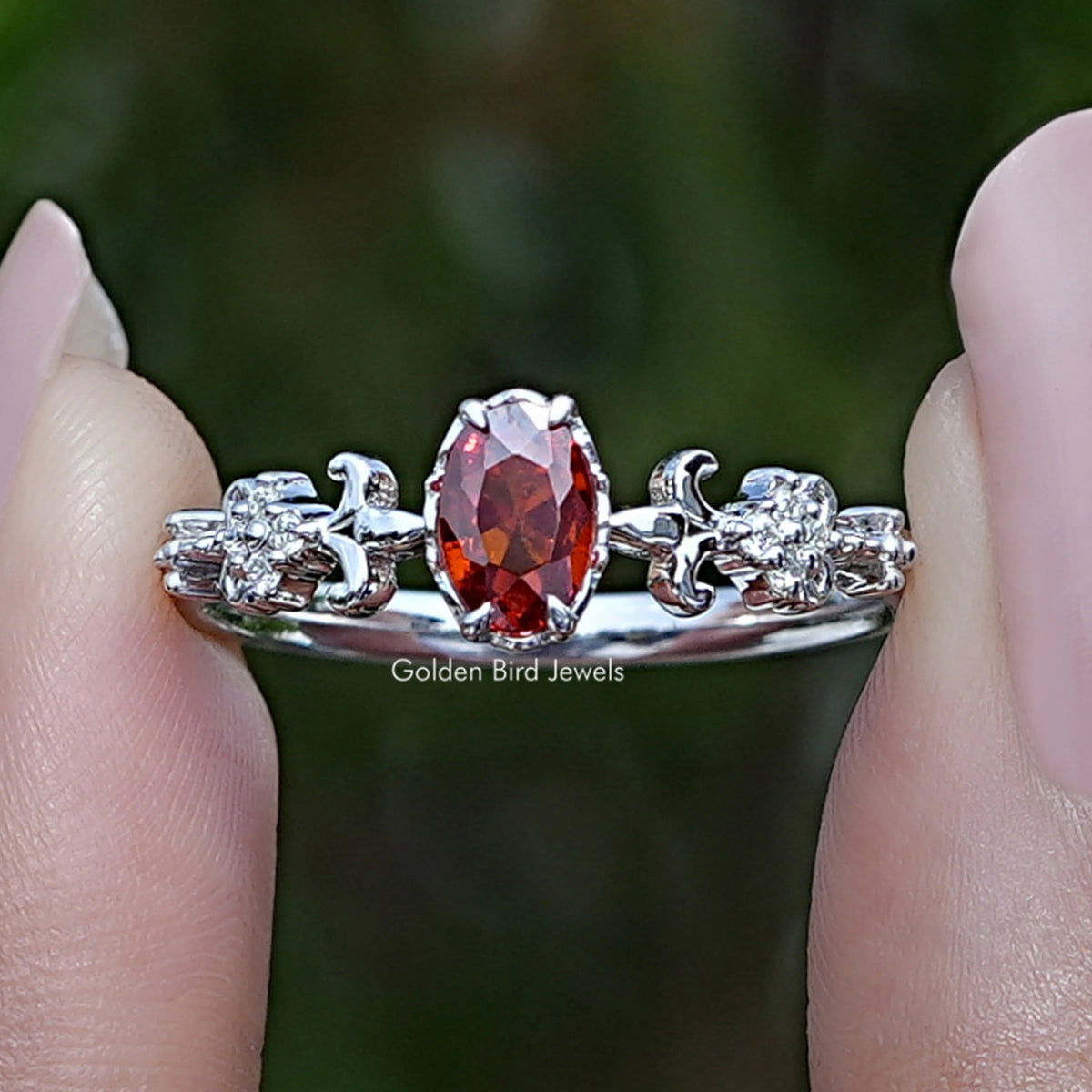 Oval red gemstone engagement ring with prong-set center and small round side stones