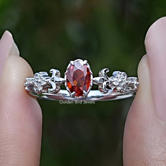 Oval red gemstone engagement ring with prong-set center and small round side stones