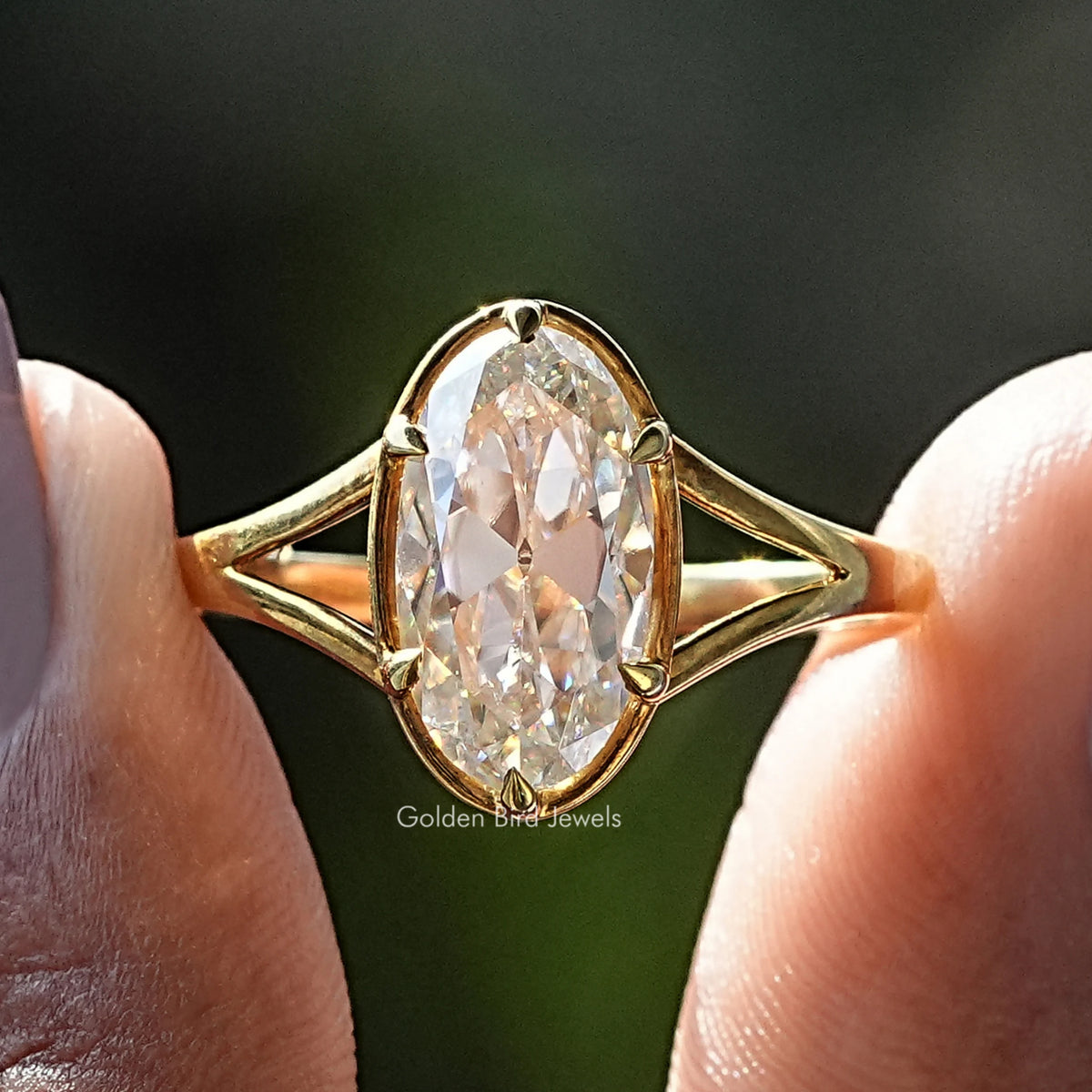 Gold-tone oval solitaire ring with clear moissanite and four-prong bezel setting