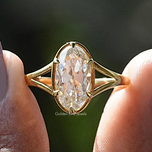Gold-tone oval solitaire ring with clear moissanite and four-prong bezel setting