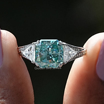 Moissanite accent stone ring with teal center and diamond-like side stones, prong set