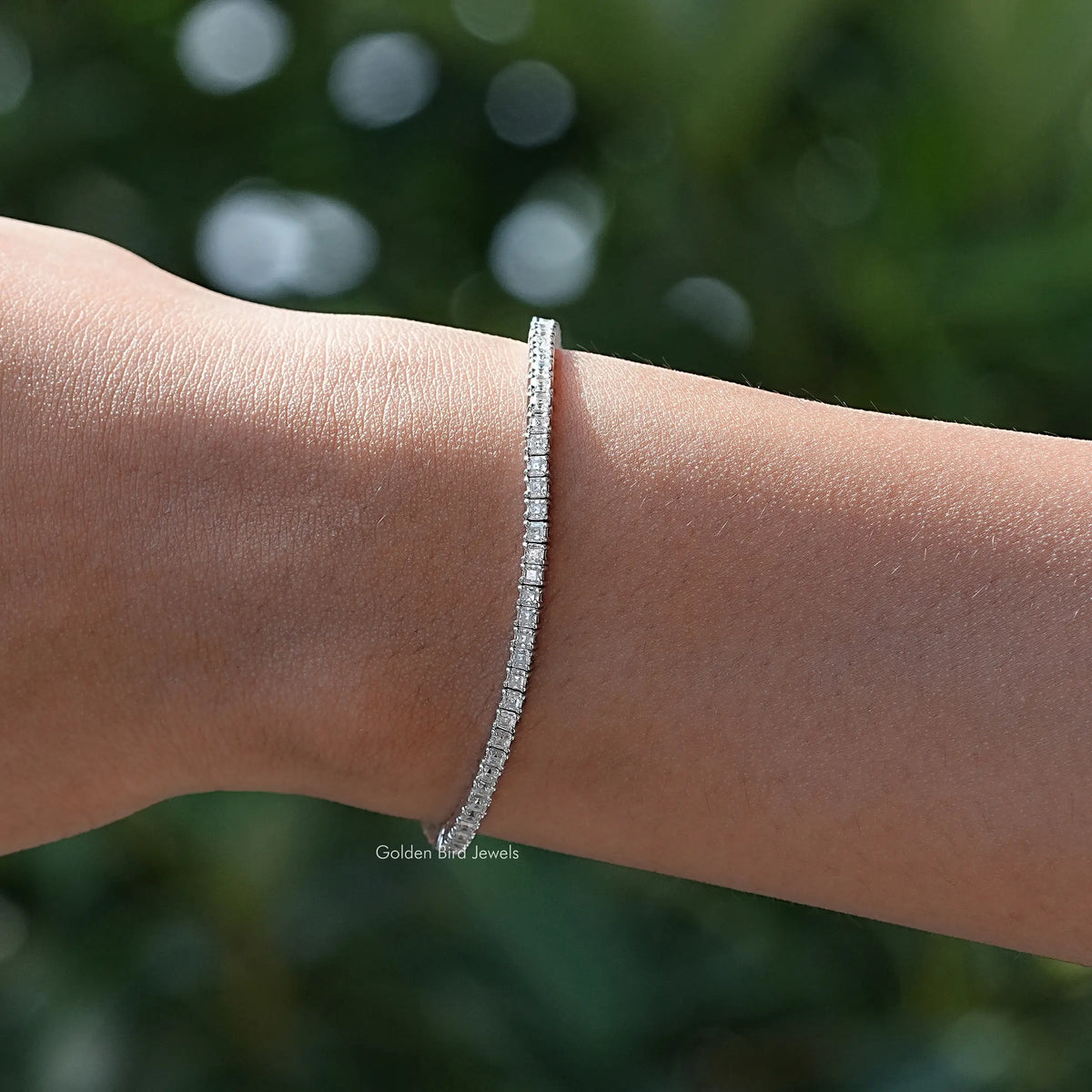 Silver tennis bracelet on wrist with closely set asscher-cut moissanite stones