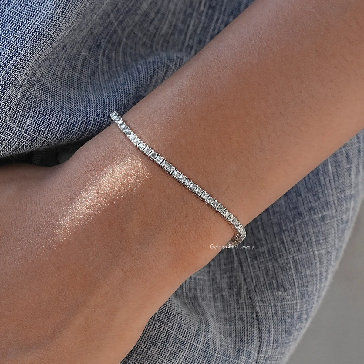 Silver tennis bracelet angled on wrist, row of asscher-cut moissanite stones