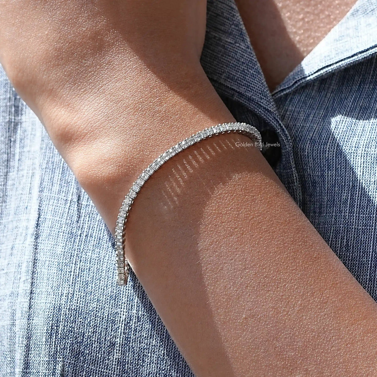 Silver tennis bracelet on arm with bright asscher-cut moissanite stone row