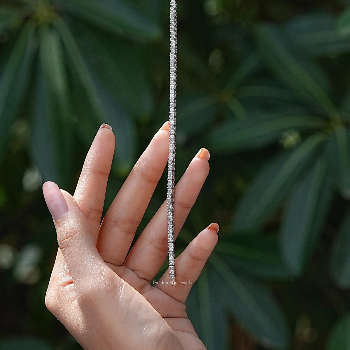 Silver tennis bracelet worn on hand, sparkling asscher-cut stones along cuff