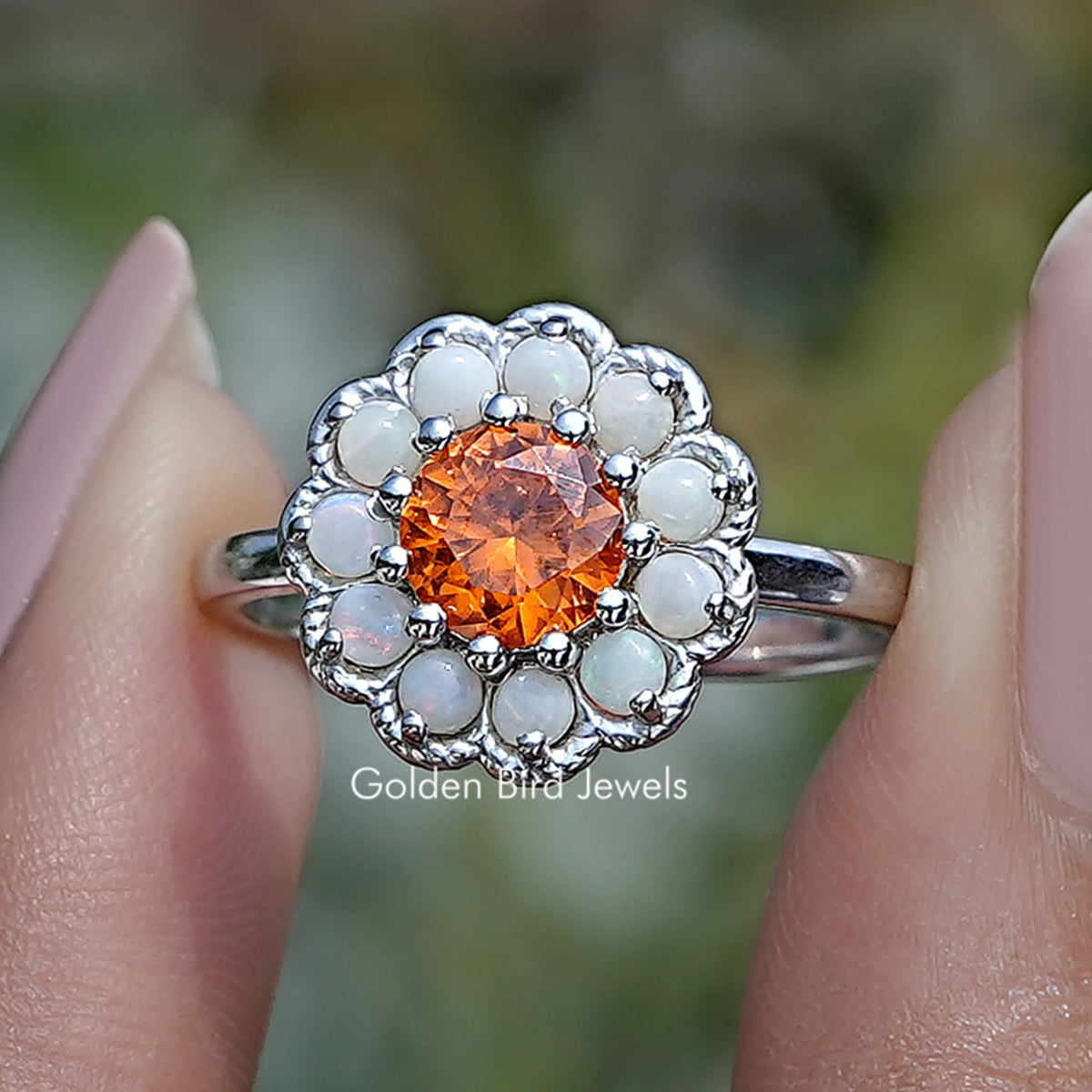 Round orange sunstone halo engagement ring in silver with white stone surround