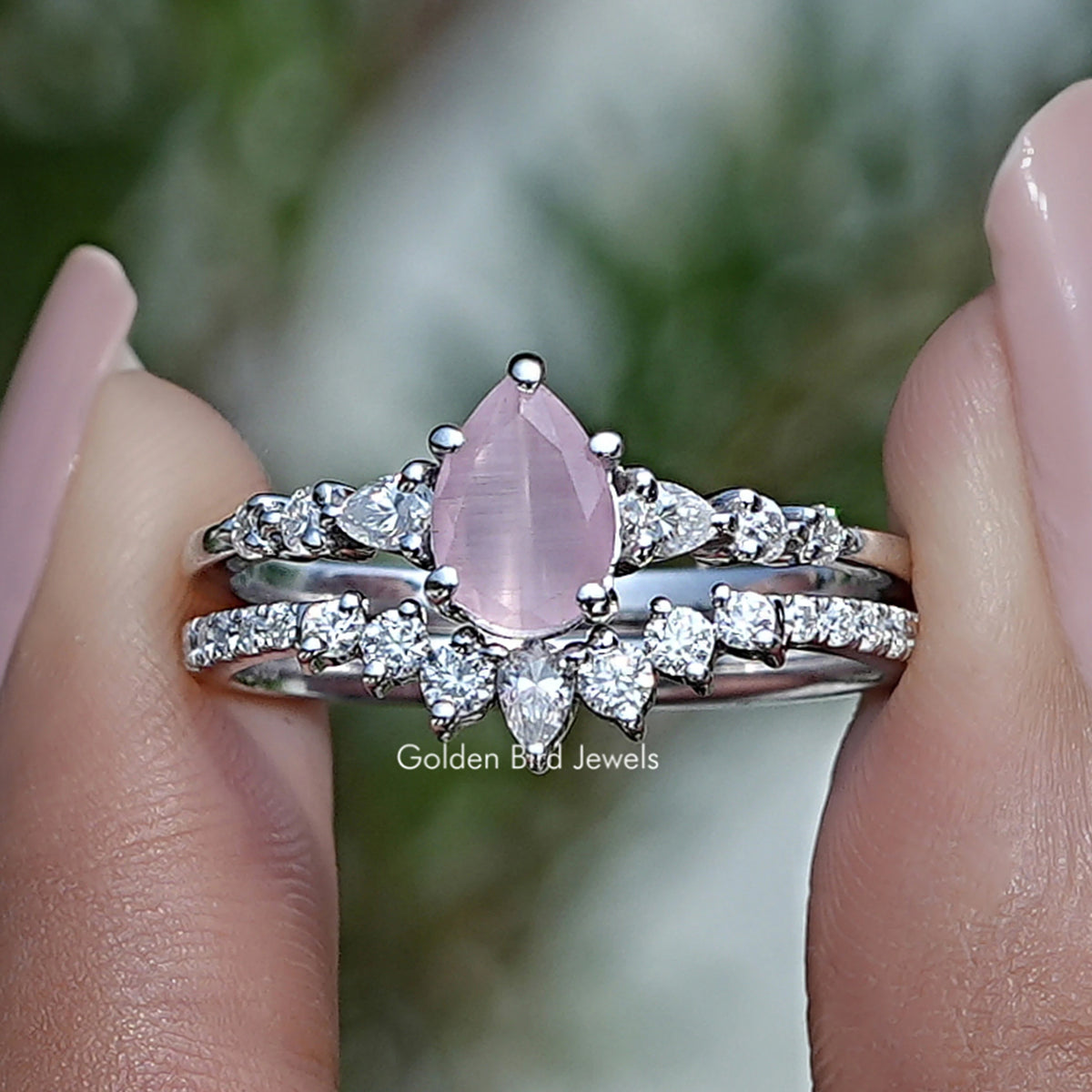 Bridal ring set with pink pear-cut gemstone center and sparkling halo accents on silver bands