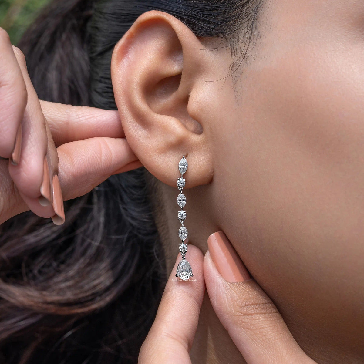 Silver drop earrings with marquise and pear-cut gemstones, shown on ear