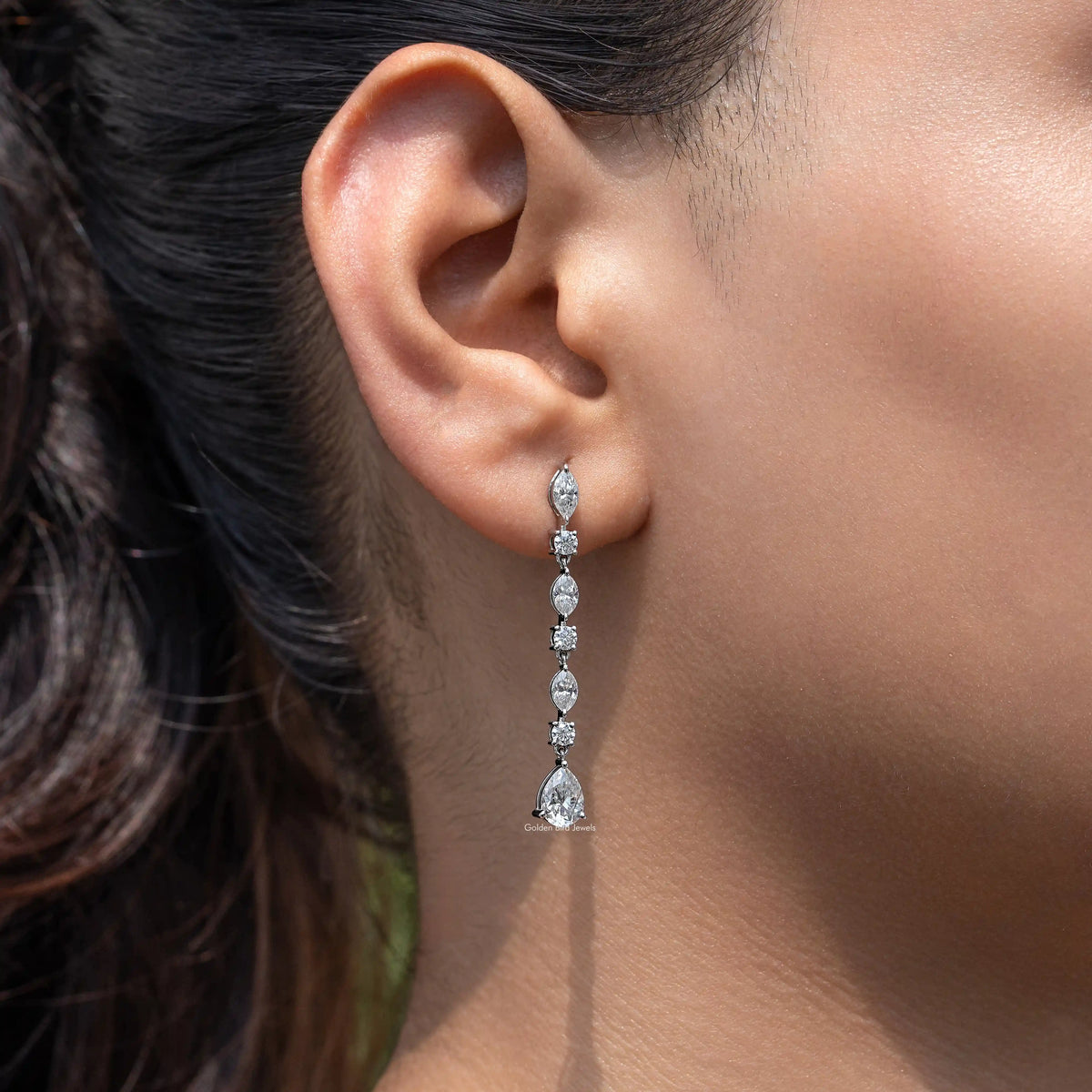 Silver drop earrings with marquise and pear-cut gemstones, side view on ear
