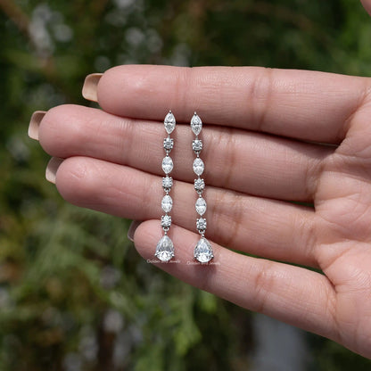 Pair of silver drop earrings with marquise and pear-cut gemstones, shown in hand