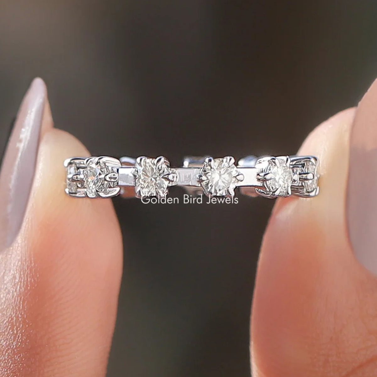 Round moissanite eternity band with silver setting and multiple clear round stones, close-up