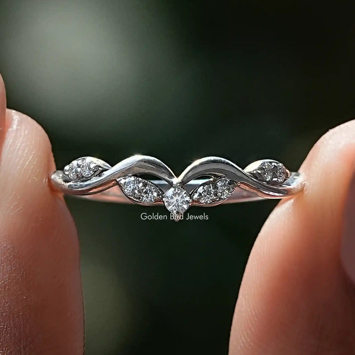 Curved silver wedding band ring with small round moissanite stones on raised arcs