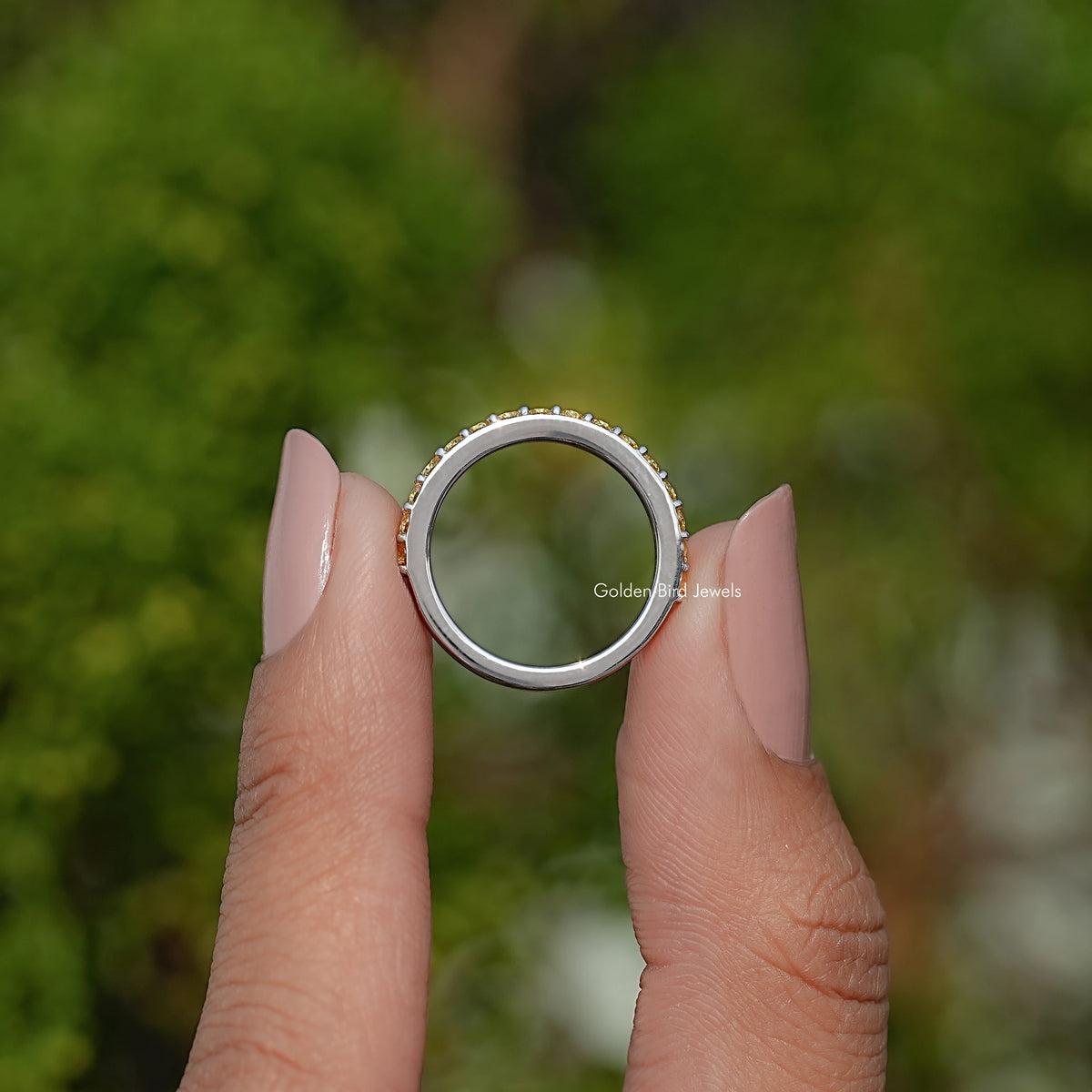 Gold-tone eternity ring with round yellow gemstones, top view on open hand