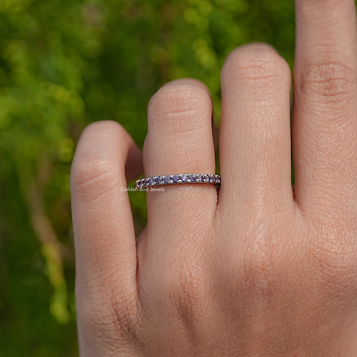 Silver amethyst eternity band ring with purple round stones on the finger
