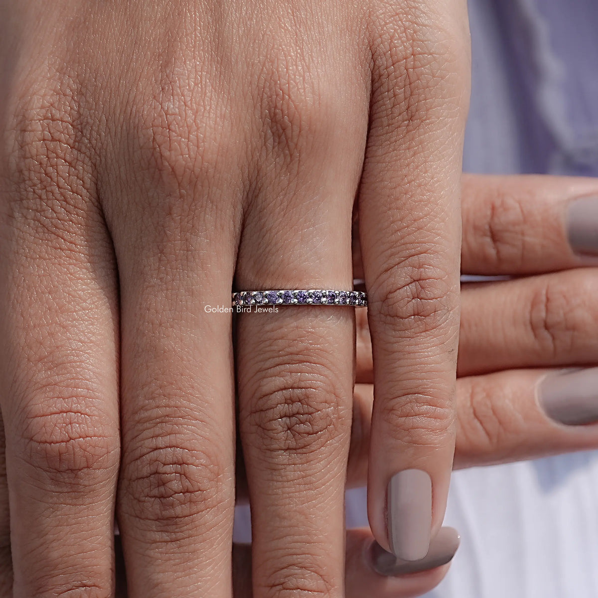 Silver amethyst eternity band ring with purple stones, close-up on fingers