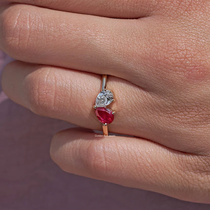 Engagement ring side view with a round diamond and red pear-cut gemstone in prongs