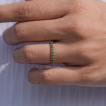 Narrow profile eternity band with green round stones, close-up view