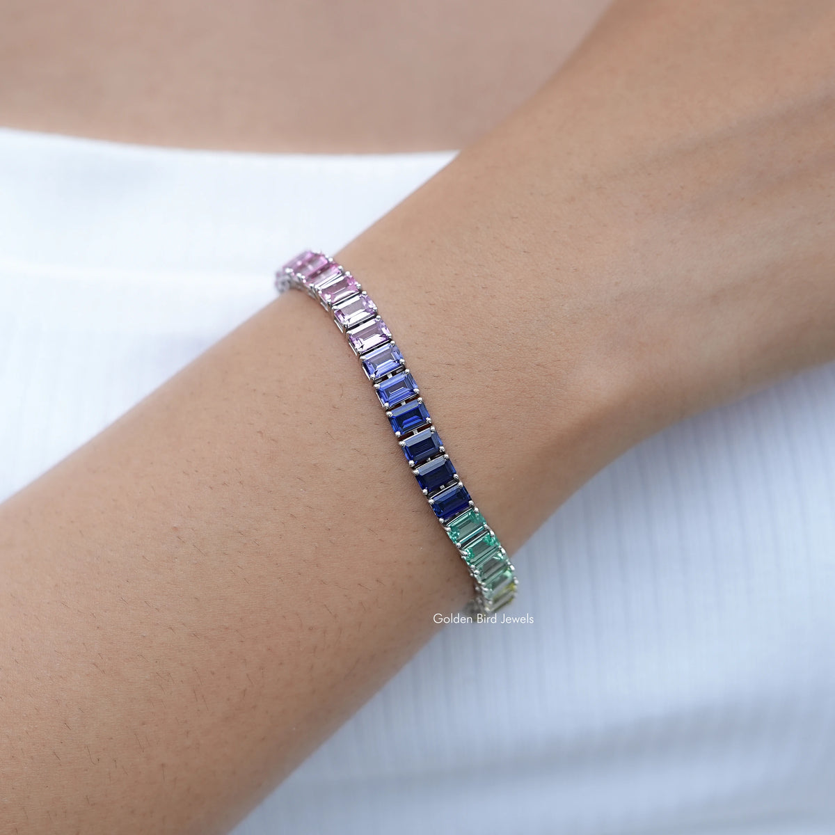 Multi-color gemstone tennis bracelet on wrist with pink, blue and green stones