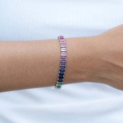 Multi-color gemstone tennis bracelet on wrist with rows of blue, green and pink stones