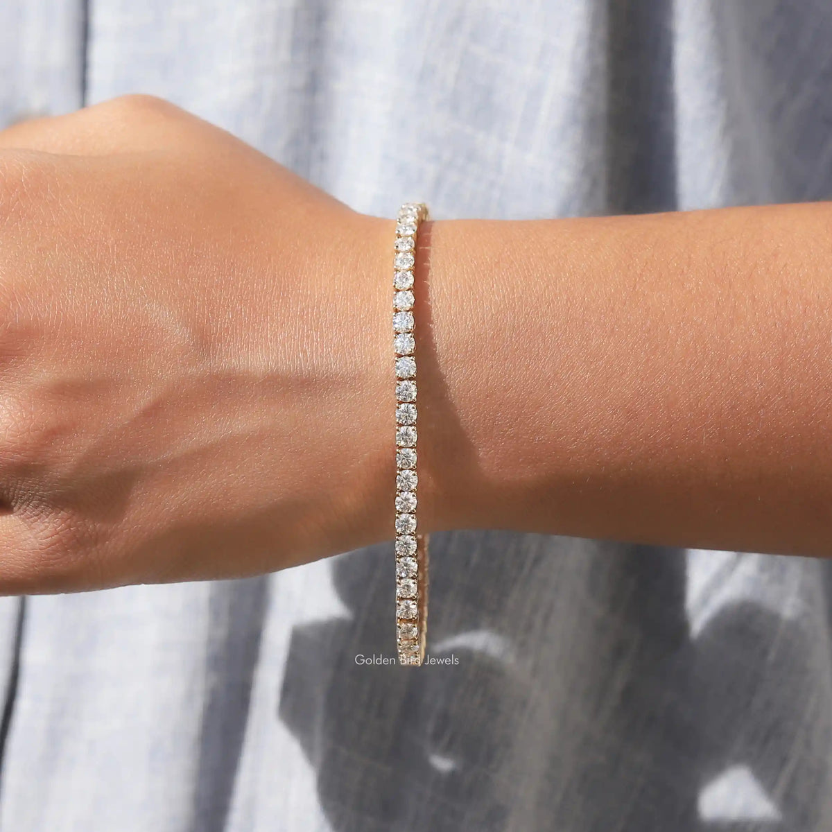 Moissanite tennis bracelet with round-cut stones, gold-tone, wrist close-up