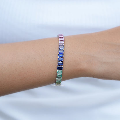 Multi-color gemstone tennis bracelet on wrist with pink top row and blue-green accents
