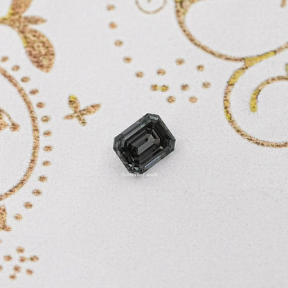 Gray emerald-cut loose gemstone with dark faceted surface, centered