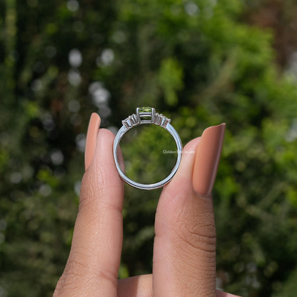 Silver ring with emerald-cut green center stone and halo, viewed from behind