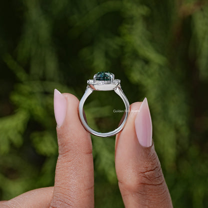 Side view of silver halo ring showing dark green oval gemstone and gallery