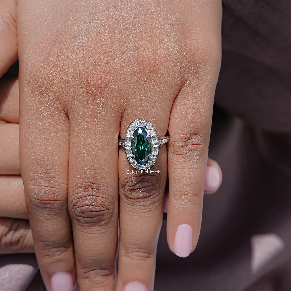 Oval halo engagement ring with dark green center gemstone and prong-set frame