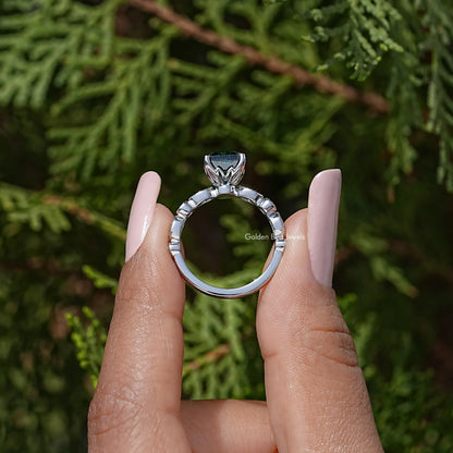 Top view of silver openwork ring with raised green Asscher-cut center stone and prong set