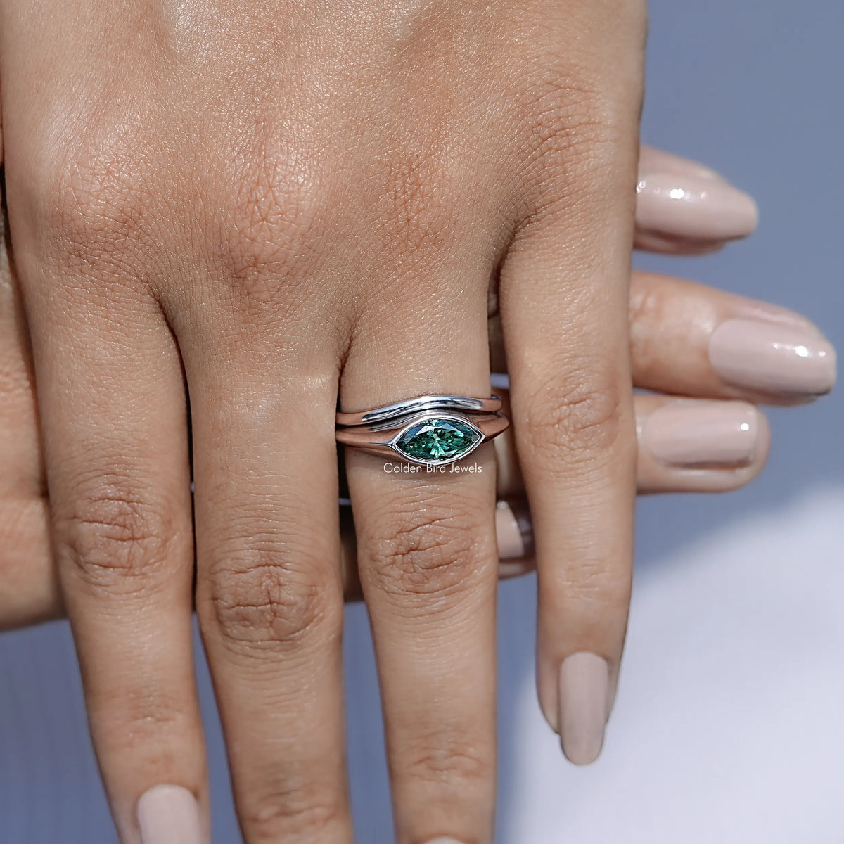 In finger front view of Green Marquise Bezel Set Moissanite Ring in unique shape