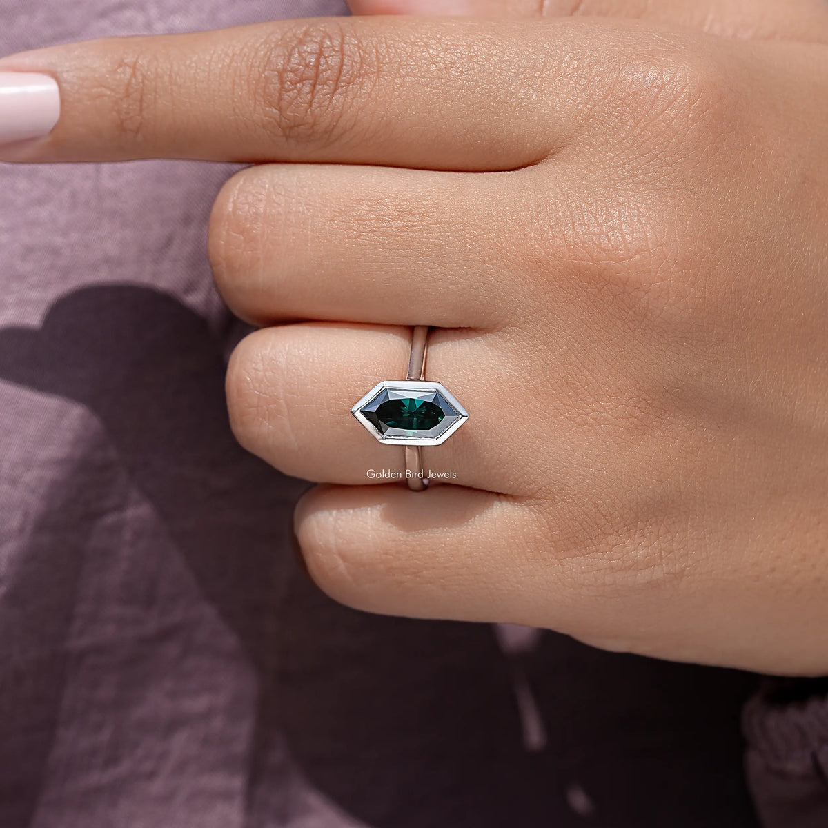 Sterling silver ring with emerald green marquise gemstone on a rose-tone background