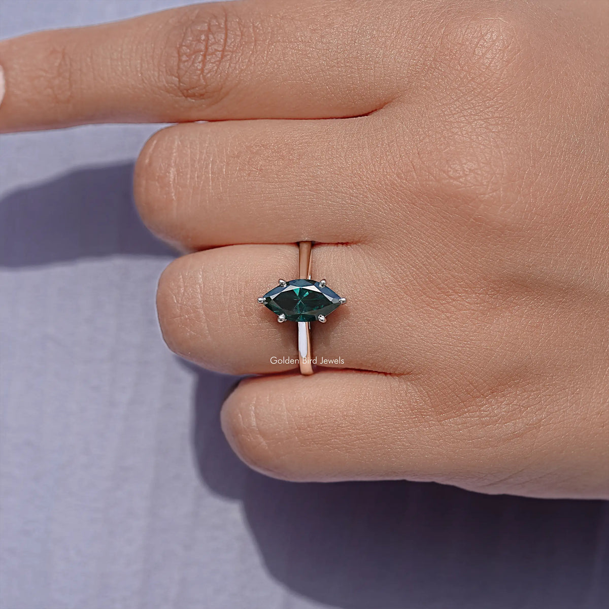 Silver solitaire ring with marquise teal gemstone on a slim band