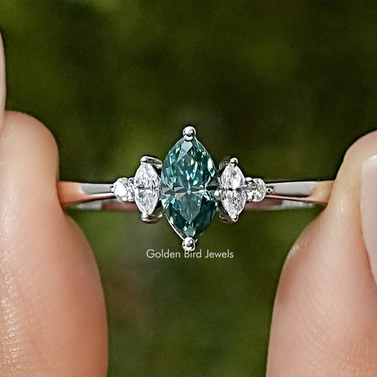 Three-stone engagement ring with green marquise center and two diamond-like side stones