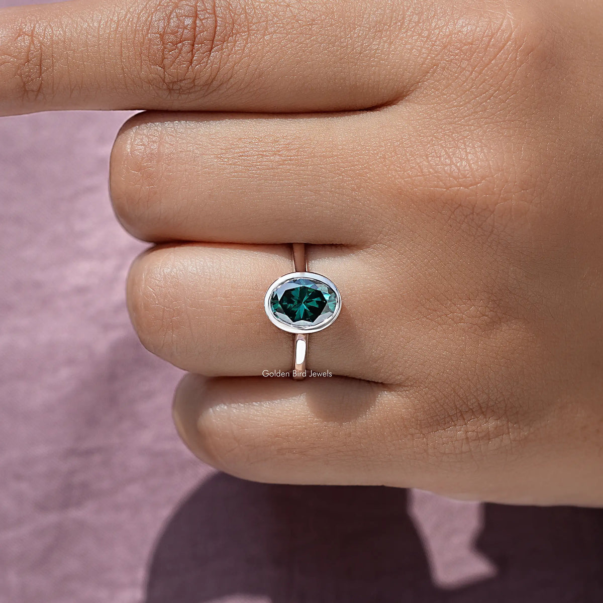 Oval moissanite solitaire ring with teal bezel-set stone, sterling silver band