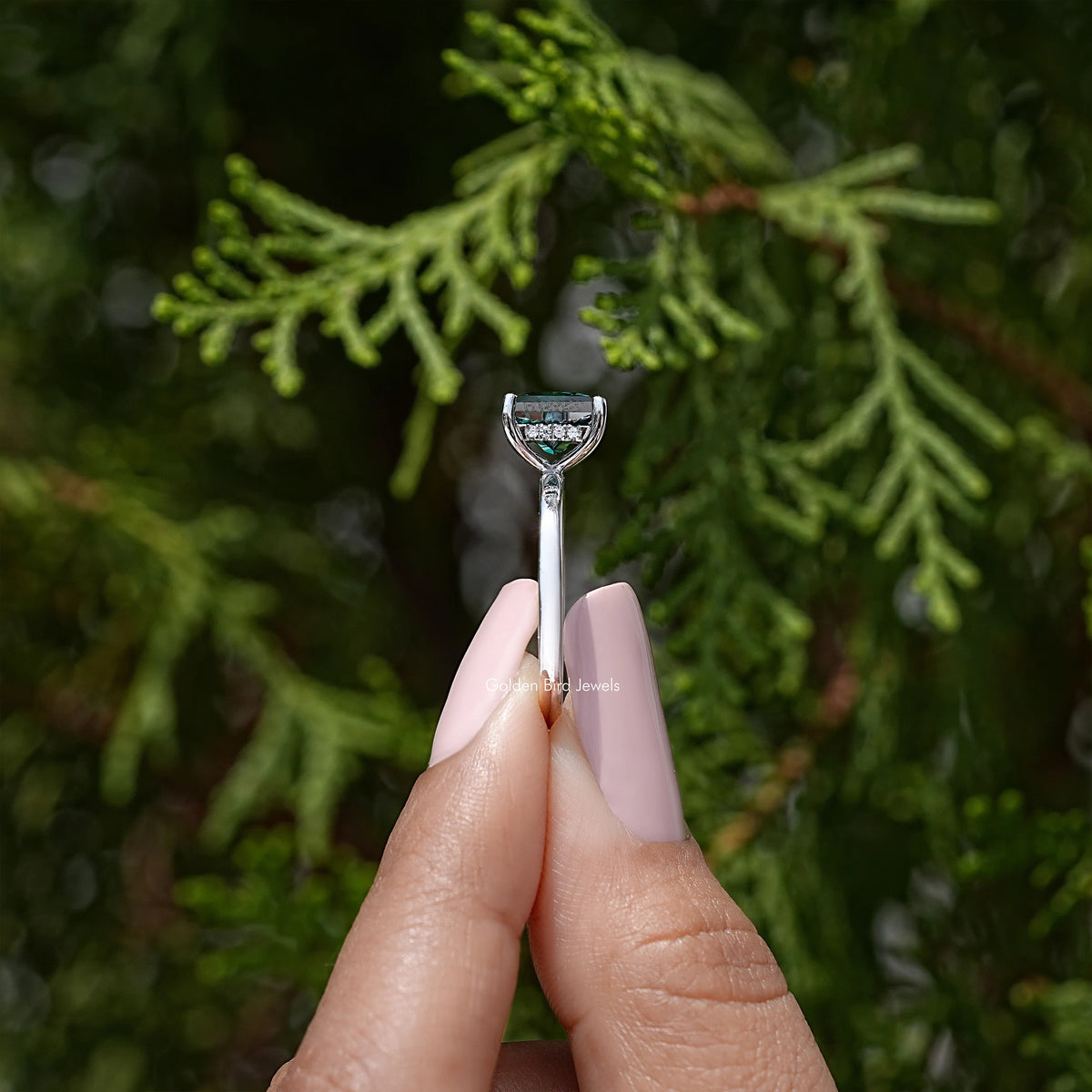 Side view of silver ring with square emerald-green center stone and hidden halo accents