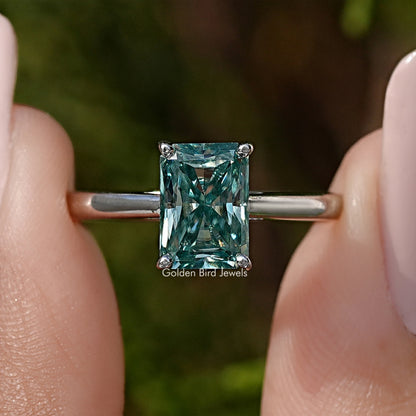 Sterling silver solitaire ring with emerald-cut blue-green moissanite center.